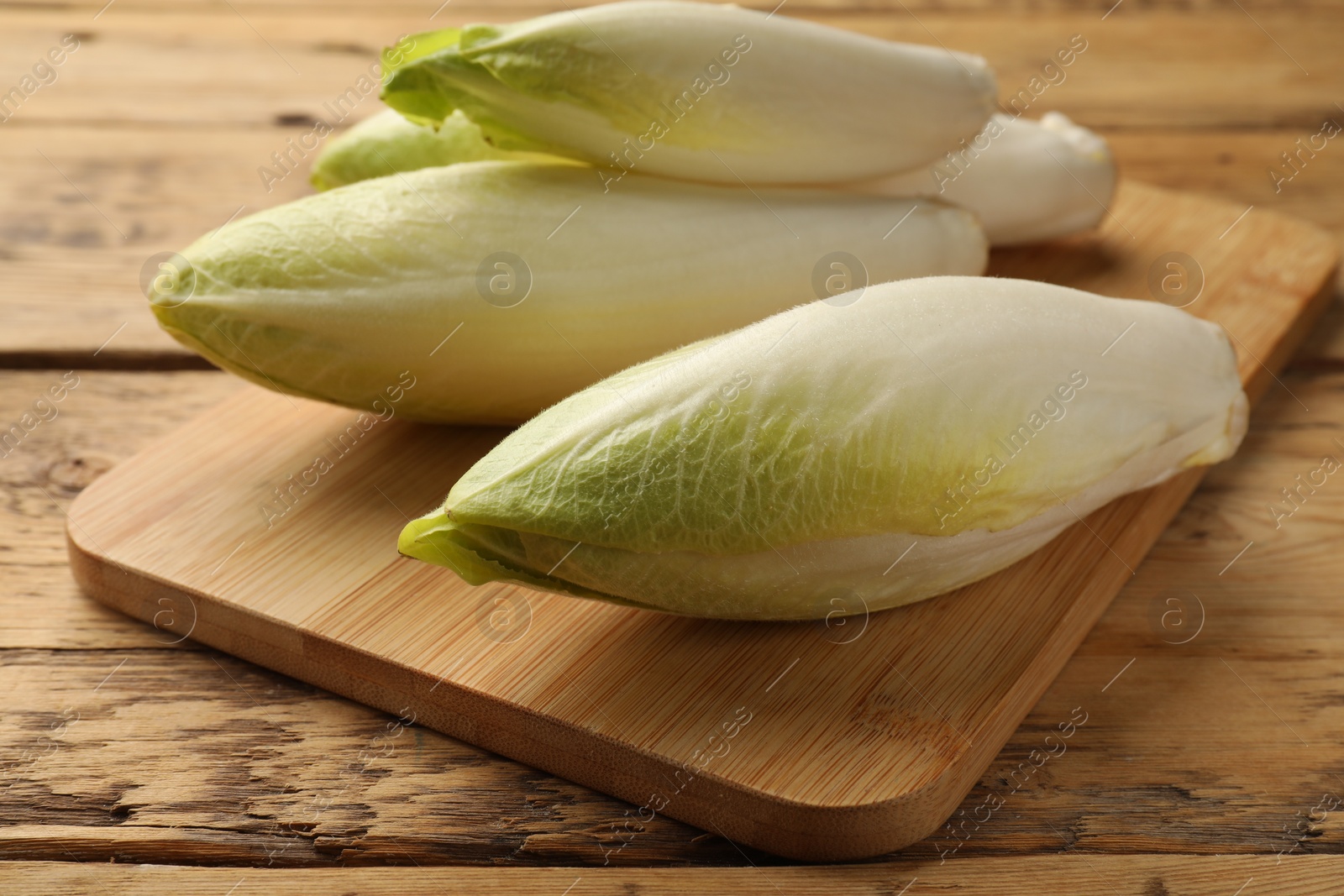 Photo of Fresh raw Belgian endives (chicory) on wooden table, closeup