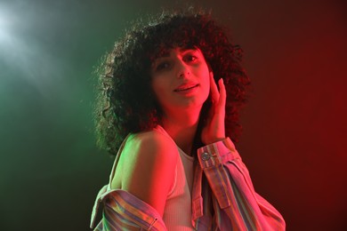 Photo of Beautiful young woman posing on color background in neon lights