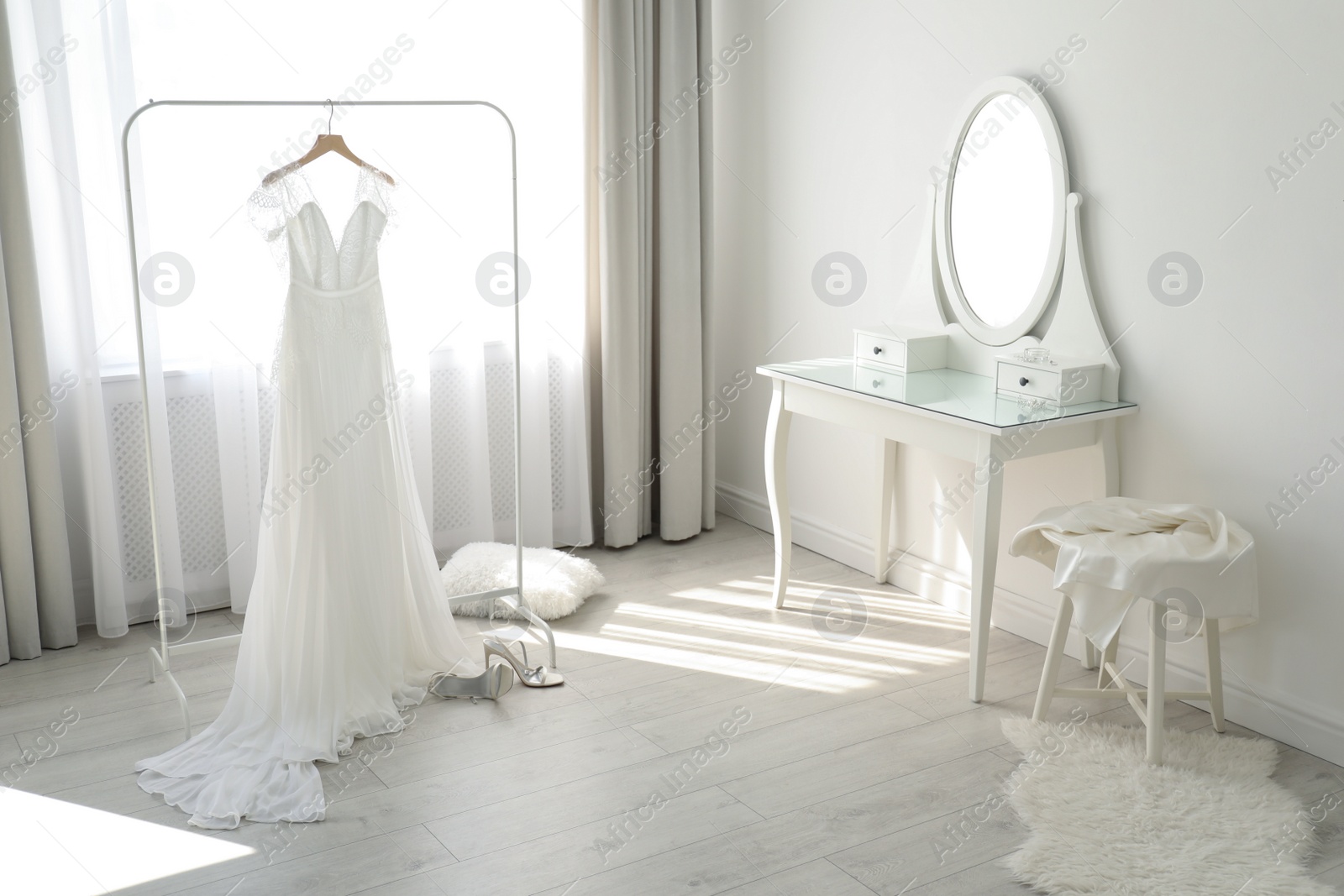 Photo of Beautiful wedding dress hanging on clothing rack in room