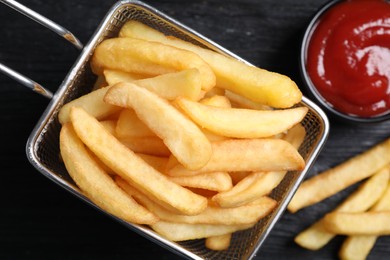 Photo of Tasty french fries and ketchup on dark wooden table, flat lay