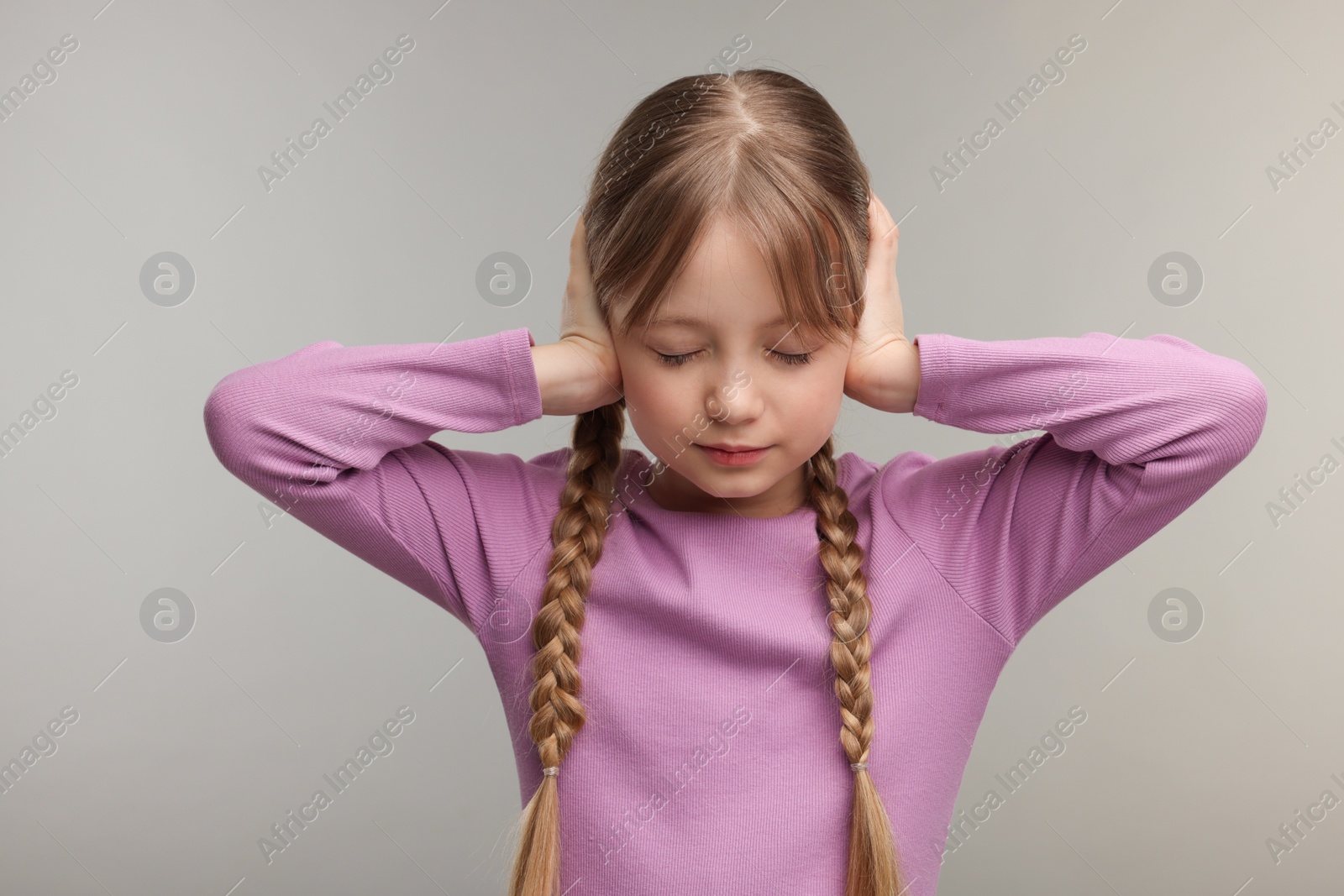 Photo of Hearing problem. Little girl suffering from ear pain on grey background