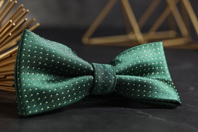 Stylish green bow tie on black table, closeup