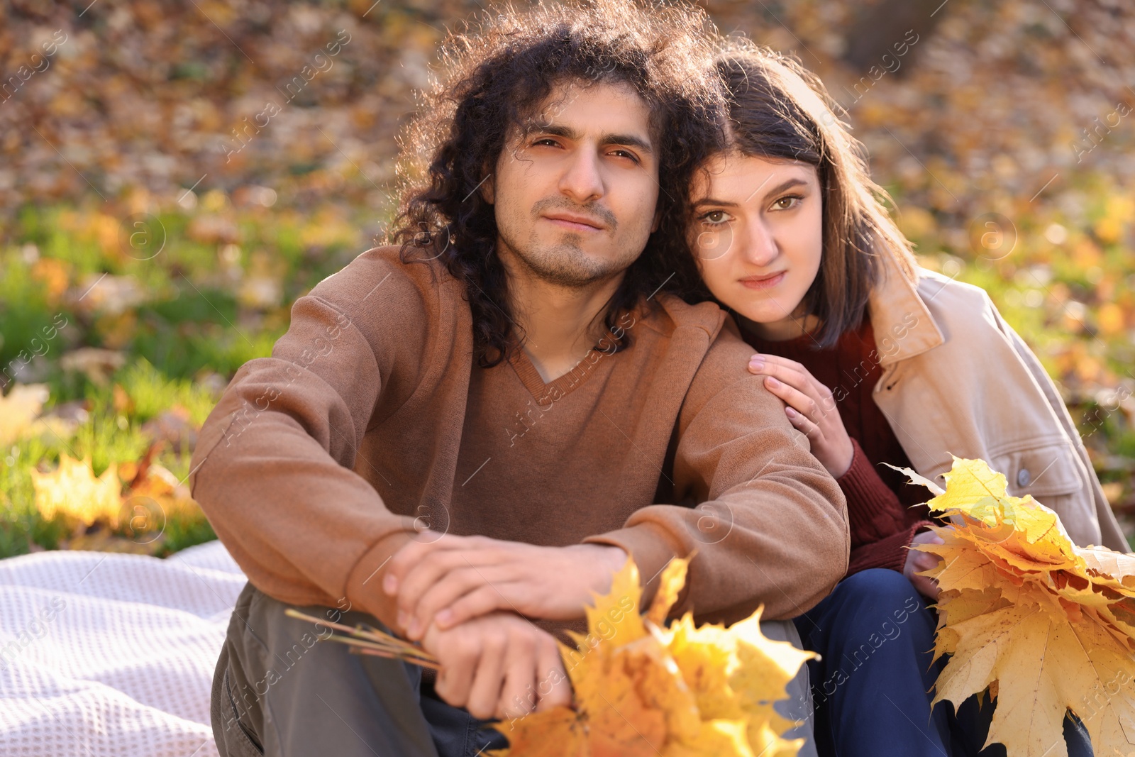 Photo of Happy young couple with dry leaves spending time together in autumn park. Dating agency