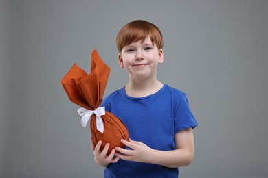 Photo of Easter celebration. Cute little boy with wrapped egg on grey background