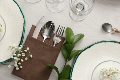 Elegant table setting with green plants on white wooden background, flat lay