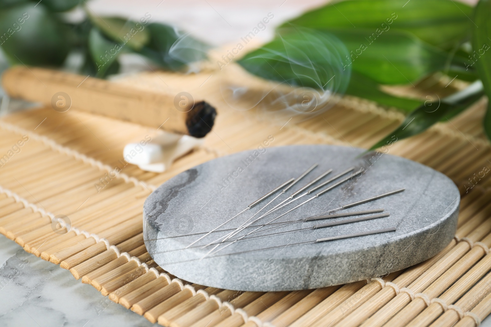 Photo of Grey stone coaster with acupuncture needles on bamboo mat