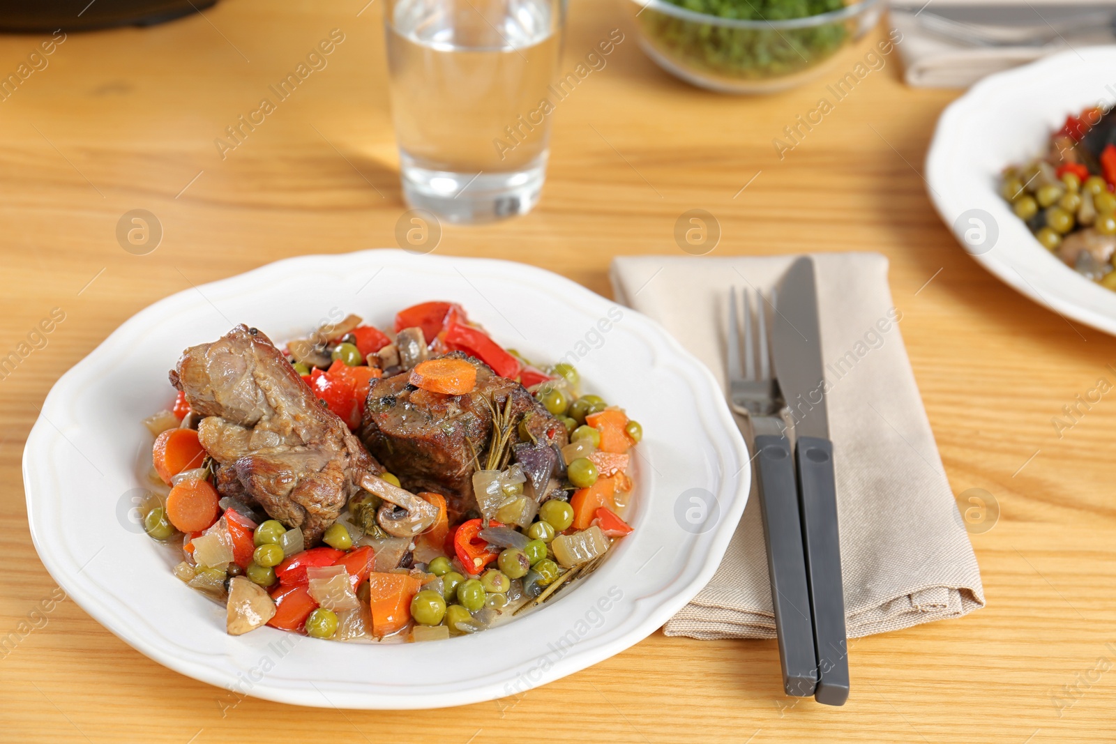 Photo of Plate with meat and garnish prepared in multi cooker served on wooden table