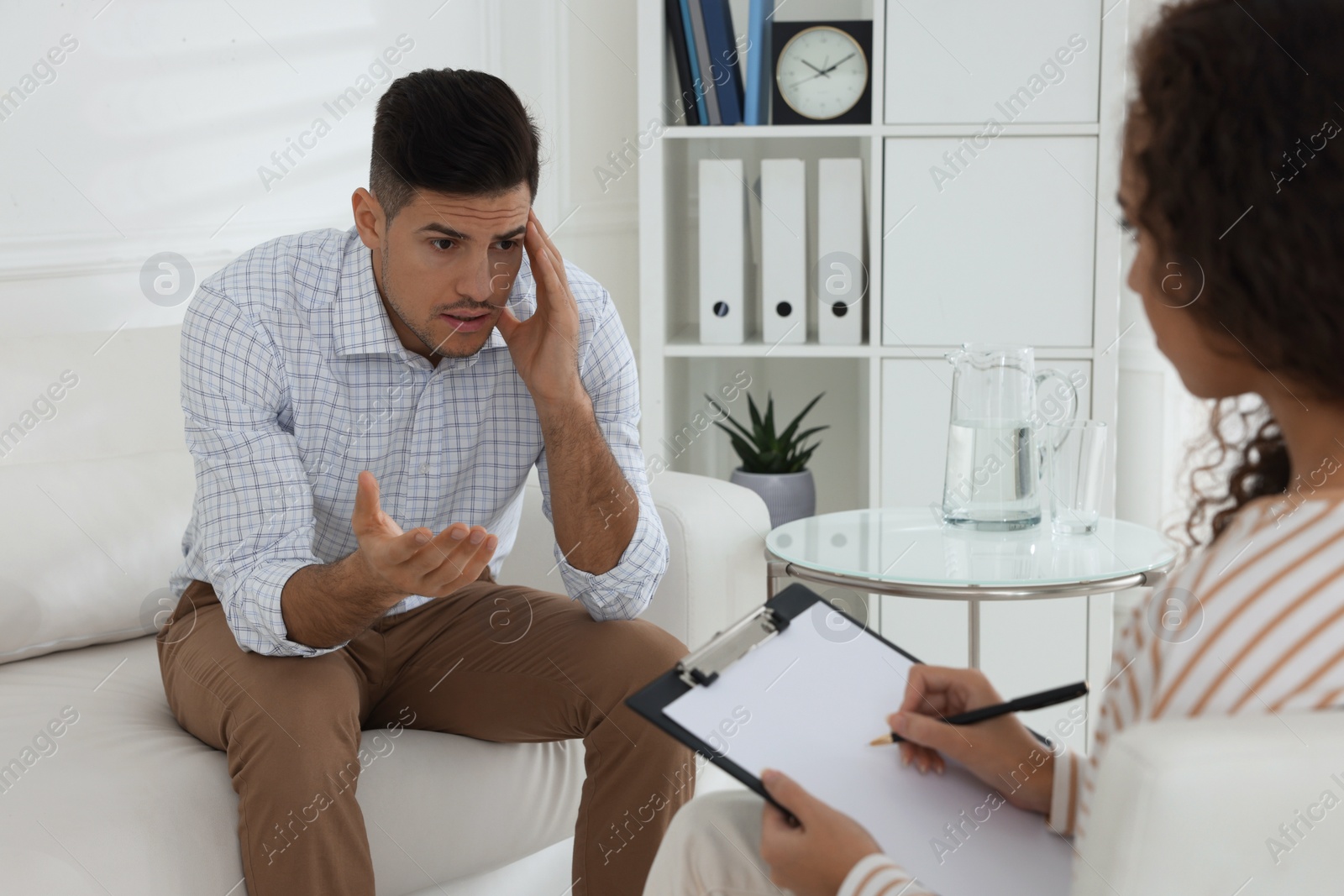 Photo of Unhappy man having session with his therapist indoors