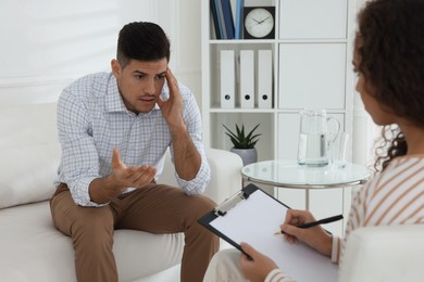 Unhappy man having session with his therapist indoors