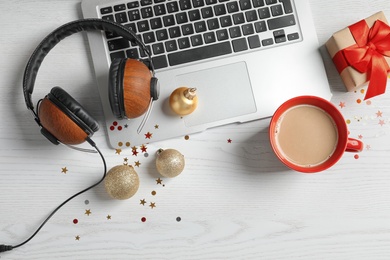 Flat lay composition with laptop, headphones and cup of coffee on wooden background. Christmas music concept