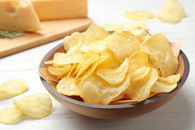 Photo of Delicious crispy potato chips in bowl on table