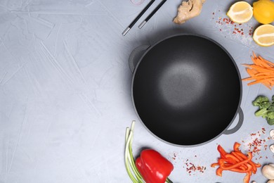 Photo of Wok, chopsticks and different products on grey table, flat lay. Space for text