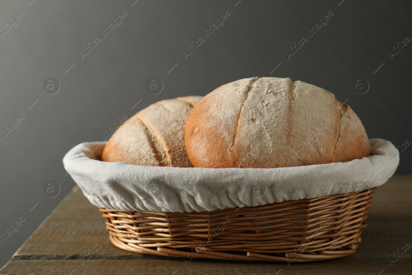 Photo of Wicker basket with fresh bread on wooden table