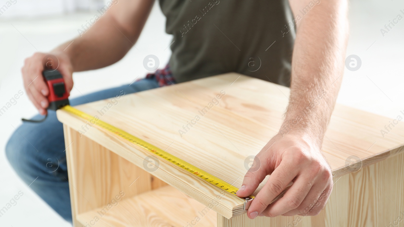 Photo of Young working man using measure tape at home, closeup