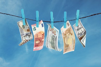 Image of Money laundering. Banknotes hanging on clothesline against blue sky