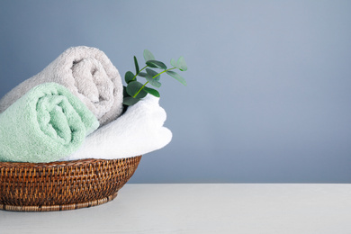 Photo of Fresh towels and eucalyptus branches on light wooden table, space for text