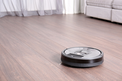 Hoovering floor with modern robotic vacuum cleaner indoors. Space for text