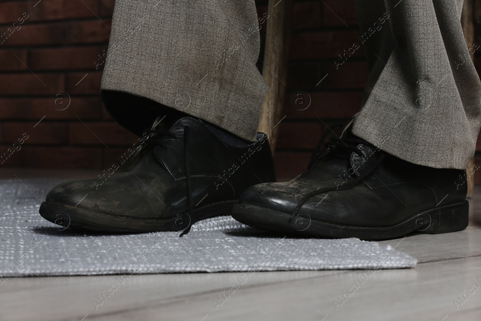Photo of Poor man wearing old dirty shoes indoors, closeup