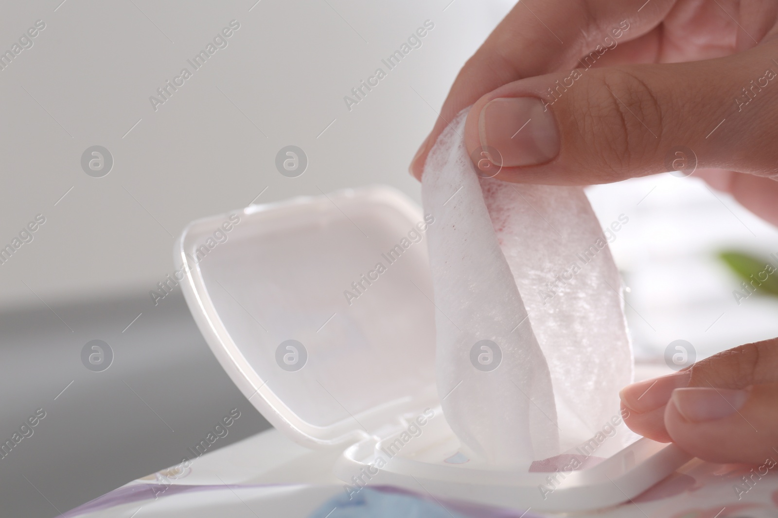 Photo of Woman taking wet wipe from pack on blurred background, closeup