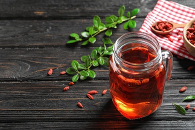 Photo of Healthy goji juice in mason jar on wooden table, space for text