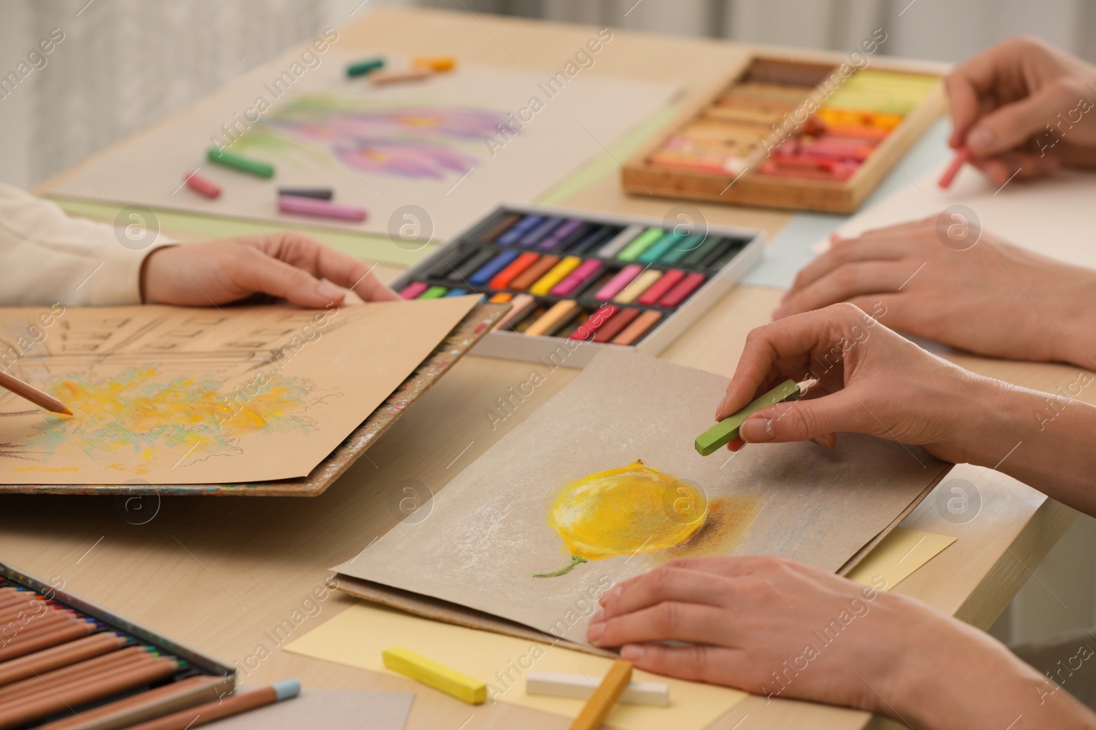 Photo of Artists drawing with soft pastels and pencils at table, closeup