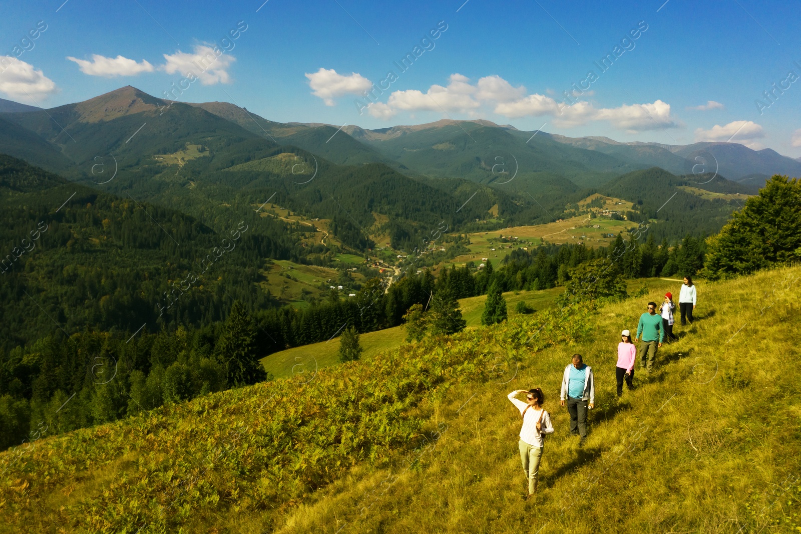 Image of Group of tourists walking on hill in mountains. Drone photography