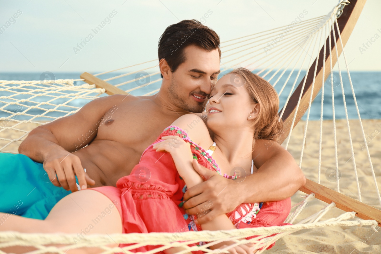 Photo of Beautiful young couple resting in hammock at sea beach