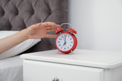 Photo of Man turning off alarm clock in bedroom