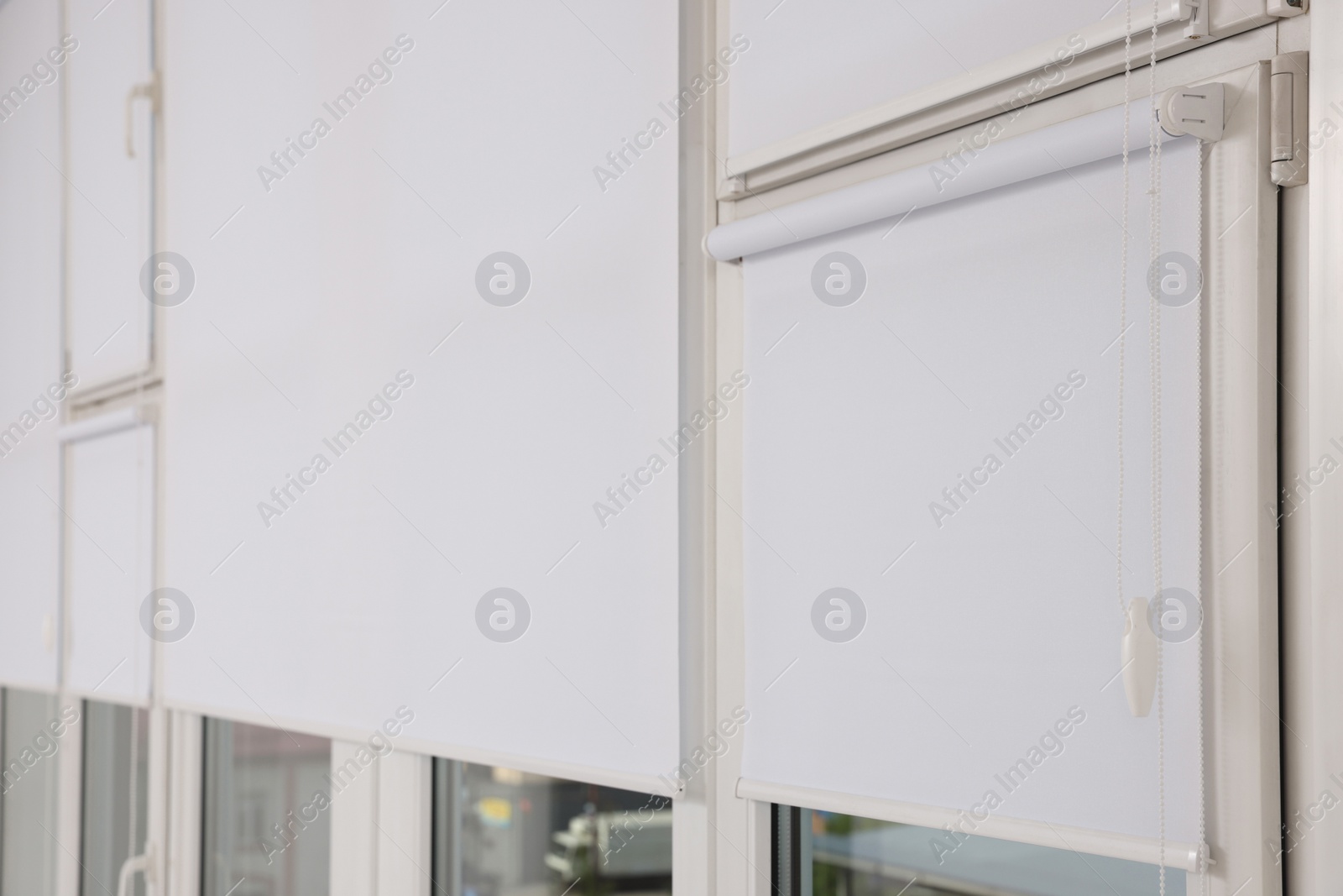 Photo of Plastic windows with white roller blinds indoors