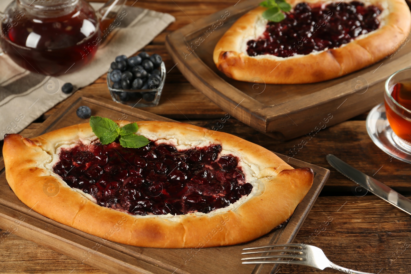 Photo of Delicious sweet cottage cheese pastry with cherry jam on wooden table