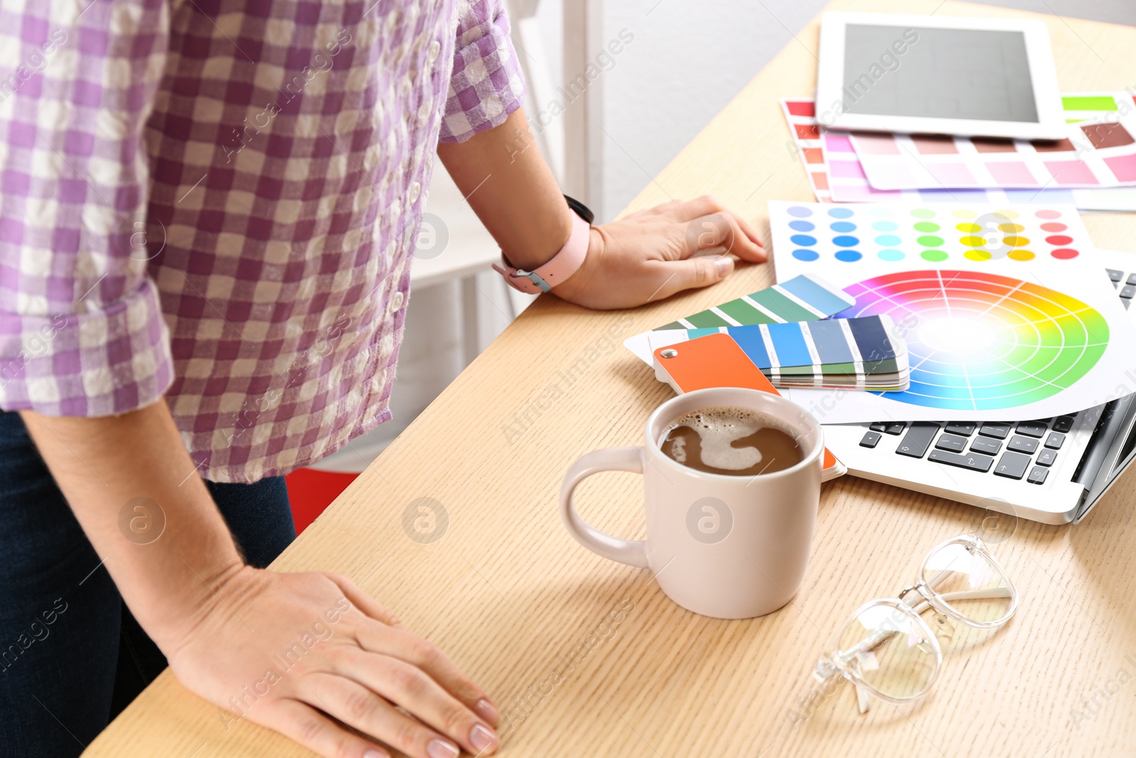 Photo of Woman working with palette samples at wooden table, closeup