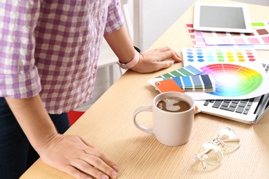 Woman working with palette samples at wooden table, closeup