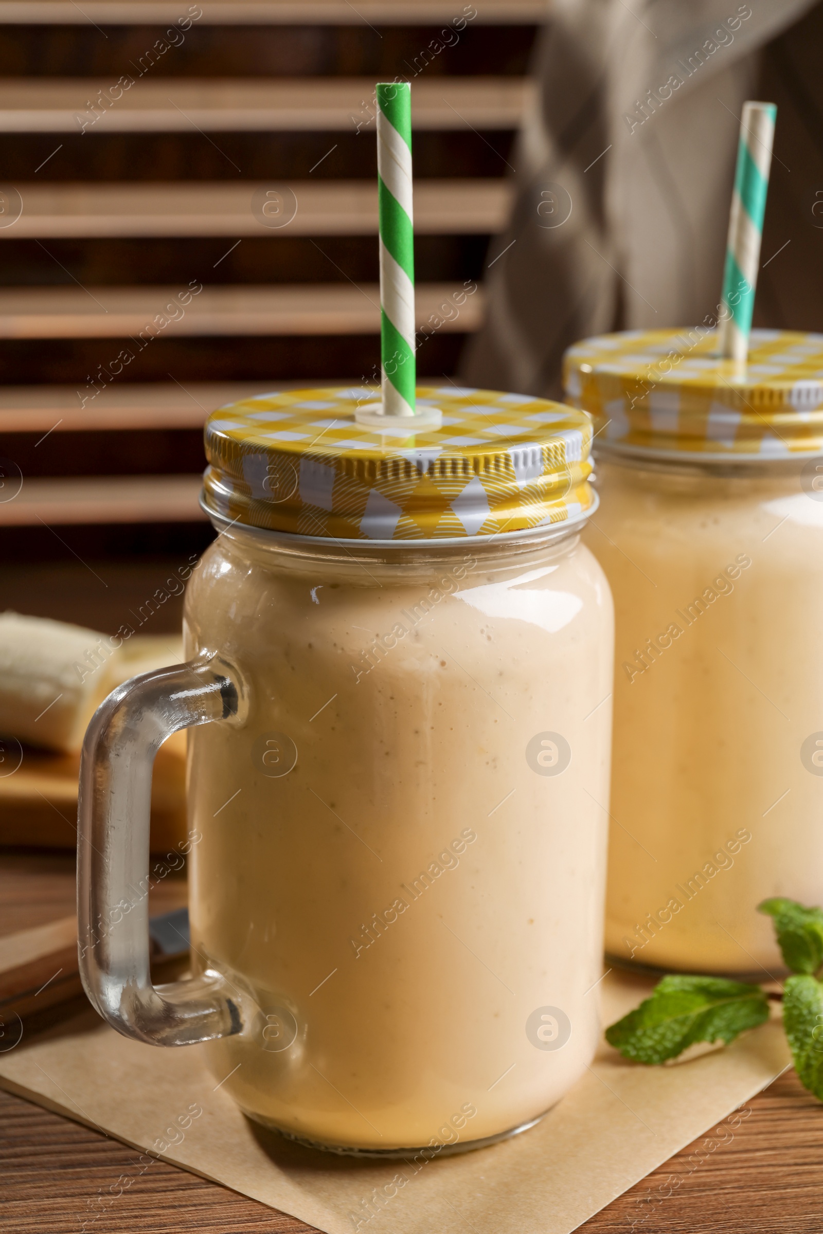 Photo of Tasty banana smoothie and mint on wooden table