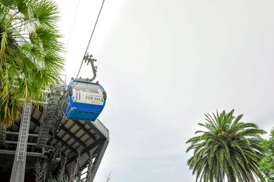 BATUMI, GEORGIA - MAY 31, 2022: Cableway with cabin against cloudy sky, low angle view