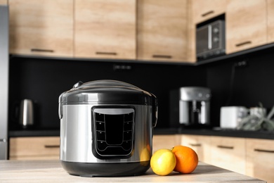 Modern multi cooker and ingredients on table in kitchen. Space for text