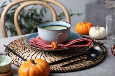 Seasonal table setting with pumpkins and other autumn decor in dining room