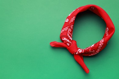 Photo of Tied red bandana with paisley pattern on light green background, top view. Space for text