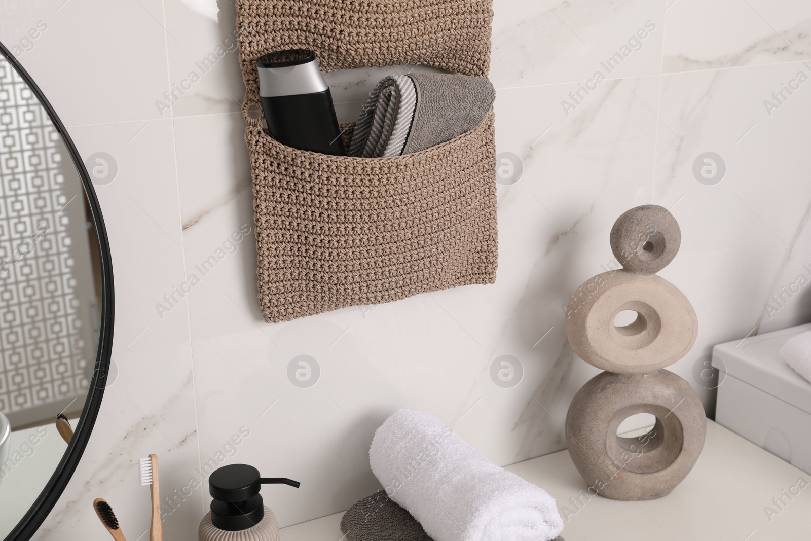 Photo of Knitted organizer hanging on wall in bathroom