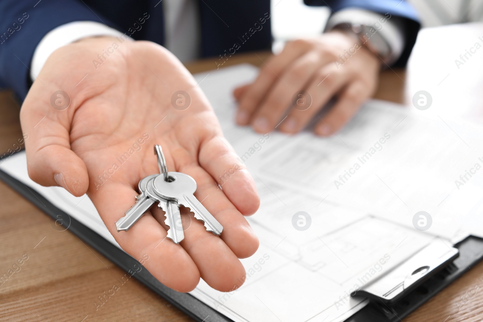 Photo of Real estate agent with keys at table in office, closeup