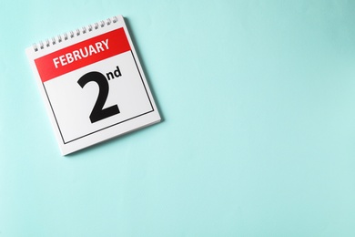Photo of Top view of calendar with date February 2nd on light blue background, space for text. Groundhog day