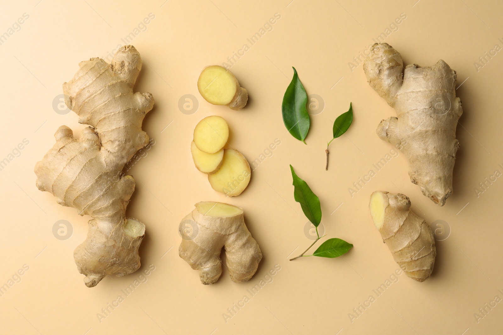 Photo of Fresh ginger with green leaves on beige background, flat lay