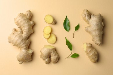 Fresh ginger with green leaves on beige background, flat lay