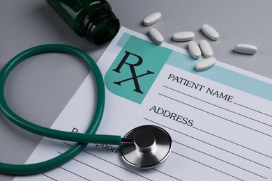 Photo of Medical prescription form, stethoscope and pills on light grey background, closeup