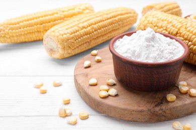 Photo of Bowl with corn starch and kernels on white wooden table, space for text