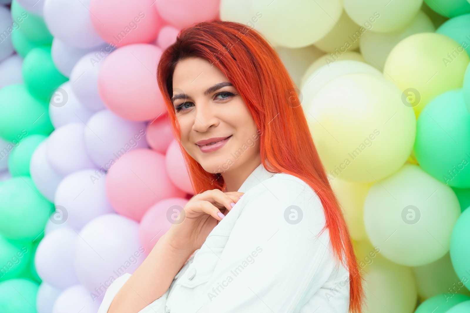 Photo of Young woman with bright dyed hair near colorful balloons