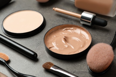 Composition with skin foundation, powder and beauty accessories on grey background