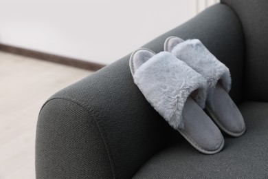 Photo of Soft grey slippers on sofa, space for text