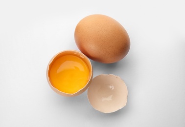 Photo of Cracked and whole chicken eggs on white background, top view