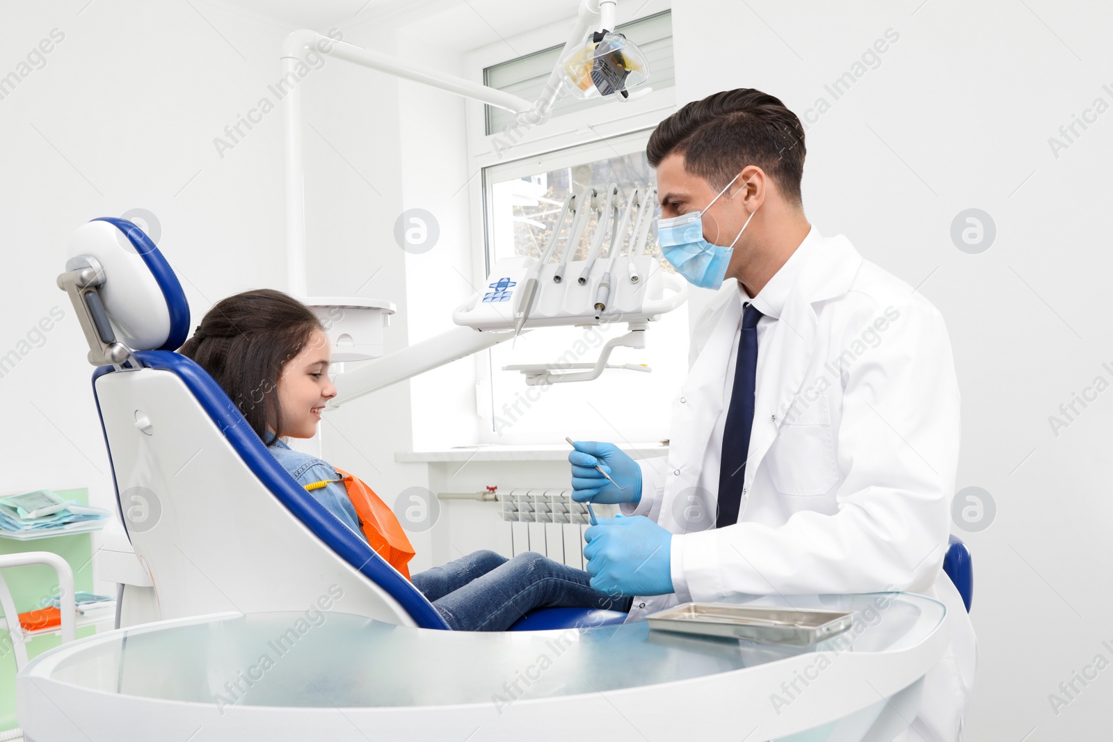 Photo of Professional dentist working with little girl in clinic