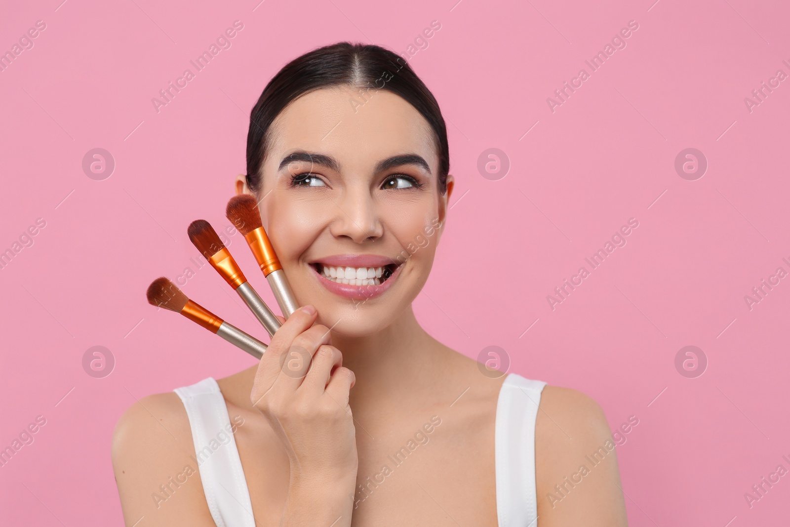 Photo of Happy woman with different makeup brushes on pink background. Space for text